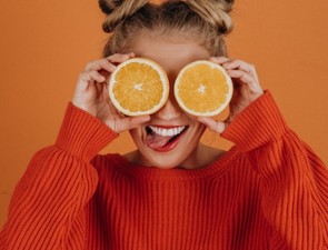 girl holding oranges infront of her eyes